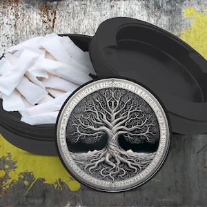 Może przedstawiać: Czarny okrągły pojemnik z pokrywką. Pokrywka ma okrągły wzór srebrnego drzewa życia z runami wokół krawędzi. Pojemnik jest wypełniony białymi papierosami.