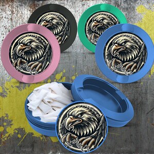 May include: Round, colorful containers with an eagle design. The containers are in various colors, including pink, green, blue, and black. One container is open, revealing white contents. The eagle illustration is detailed with a black and white color scheme.