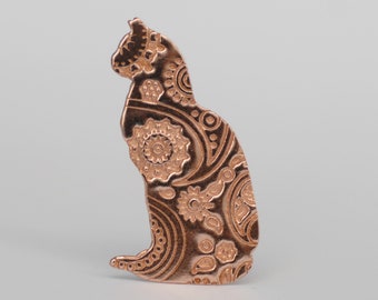 May include: A rose gold metal cat figurine with a paisley pattern.