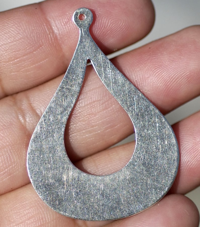 May include: Silver teardrop-shaped earring with a hole at the top for hanging. The earring has a smooth, brushed finish and a cutout in the center.