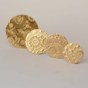 May include: Four gold-colored metal earrings with a paisley pattern. The earrings are different sizes and are arranged in a row from largest to smallest.