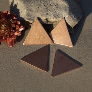 May include: Four copper-coloured triangle shapes, two larger and two smaller, arranged on a light grey surface.
