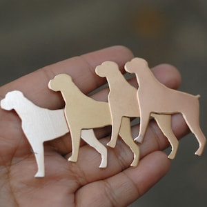 Può includere: Quattro sagome di cani in metallo di diverse dimensioni, realizzate in argento, oro e rame. Le sagome sono disposte in fila, con la sagoma più grande sul retro e la sagoma più piccola sul davanti.