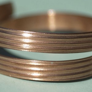 May include: A double-layered copper bracelet with a ridged design. The bracelet is a warm, reddish-brown color.