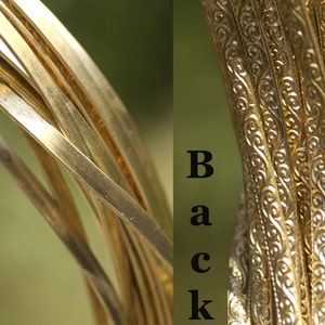 May include: Close-up of a stack of gold-colored metal wire with a decorative pattern on the back. The front of the wire is smooth and shiny. The words "Front" and "Back" are labeled on the image.