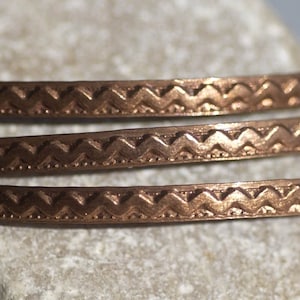May include: Three copper bangles with a chevron pattern. The bangles are stacked on top of each other.