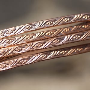 May include: Four strands of copper wire with a decorative, embossed pattern. The wire is a warm, reddish-brown color.