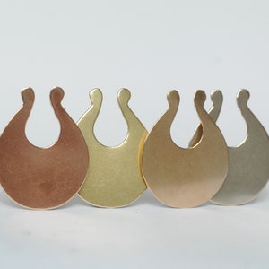 May include: Four metal pendants in different colours: copper, gold, brass, and silver. Each pendant is shaped like a stylised U with a rounded bottom.