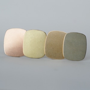 May include: Four square metal tiles in different shades of gold, from rose gold to a darker gray.