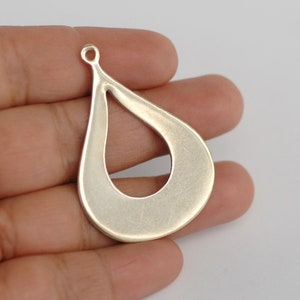 May include: Silver teardrop shaped pendant with a cut-out design. The pendant has a loop at the top for attaching to a chain or cord.
