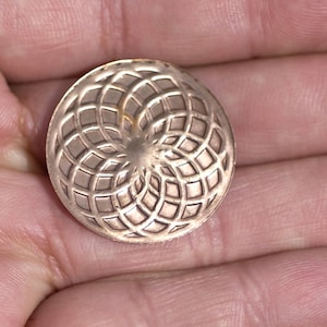May include: A copper-coloured metal pendant with a geometric design. The design is a circular pattern of overlapping circles, creating a flower-like shape.
