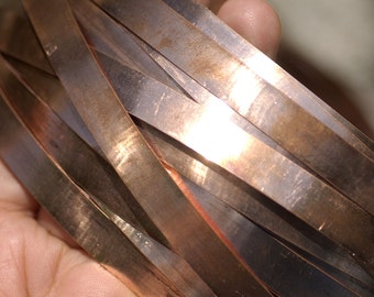 May include: A close-up of a stack of thin, flat, copper strips. The strips are arranged in a criss-cross pattern and have a warm, metallic sheen.