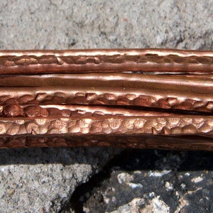 Peut inclure: Gros plan de plusieurs brins de fil de cuivre martelé. Le fil a une finition martelée texturée et est de couleur brun rougeâtre chaud.