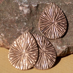 May include: Three bronze-colored, teardrop-shaped earrings with a textured, sunburst design.