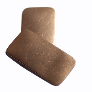 May include: Two rectangular pieces of metal with a brushed finish. The metal is a light brown colour.