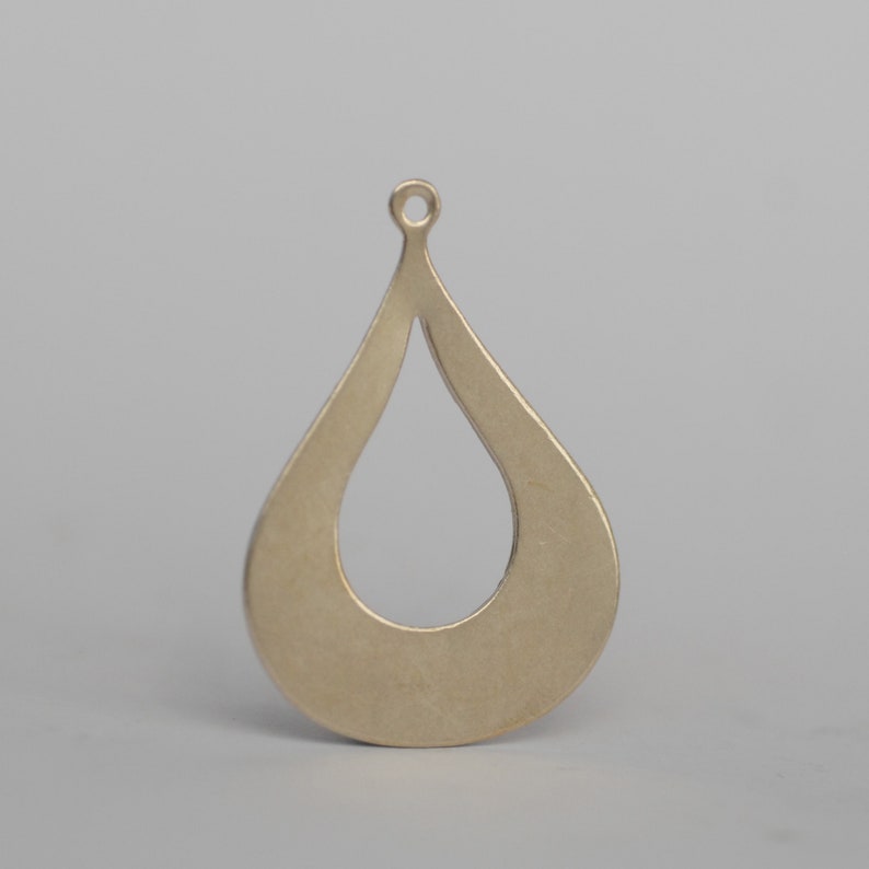 May include: A gold-toned metal pendant shaped like a teardrop with a hole at the top for hanging.