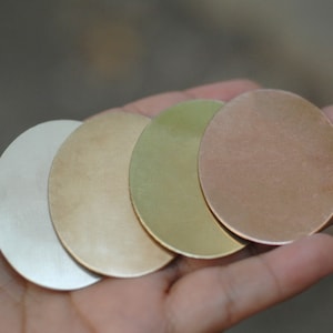 Puede incluir: Cuatro discos metálicos redondos de diferentes colores: plata, oro, latón y cobre. Los discos están apilados uno encima del otro.