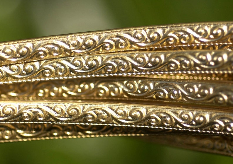 May include: Close-up of gold-colored metal trim with a decorative, swirling pattern.