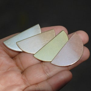 Puede incluir: Cuatro piezas de metal en forma de semicírculo en tonos de azul, rosa, verde y morado. Las piezas están dispuestas en forma de abanico, con la pieza azul en la parte superior y la pieza morada en la parte inferior.