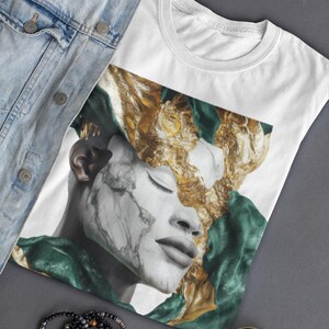 Peut inclure: T-shirt blanc avec un graphisme de visage à la peau effet marbre et des détails dorés et verts. Le t-shirt est présenté avec une veste en jean, des lunettes de soleil et un bracelet de perles.