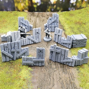 以下が含まれることがあります： 卓上ゲーム用の、グレーの3Dプリントされたミニチュアの壊れた木製の壁と箱のセットです。壁は板でできており、弾痕があります。箱は木でできており、ざらざらした質感です。