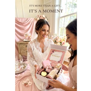 May include: A white gift box containing a pink jewelry case, a pink scrunchie, a gold-rimmed glass with the name Sophie, and a card with the text Will you be my Bridesmaid? The box lid features the text IT'S MORE THAN A GIFT... IT'S A MOMENT.