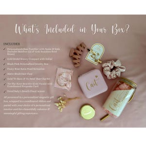 May include: A gift set including a glass tumbler with a bamboo lid and gold straw, a blush pink jewelry box labeled Cait, a dusty rose pearl scrunchie, a matte blush hair claw, a gold hair clip set, a gold bracelet, and dried flowers.
