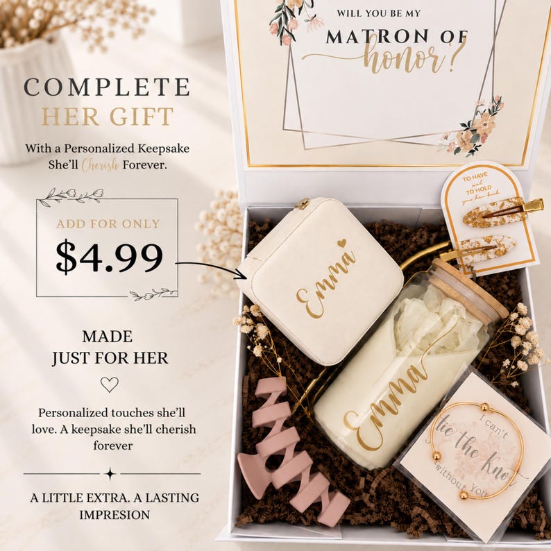 May include: A gift box containing a white jewelry case with the name Emma, a glass tumbler with a bamboo lid and the name Emma, two gold-flecked hair clips, a pink hair claw, and a gold-toned bracelet on a card reading I can't tie the knot without you.