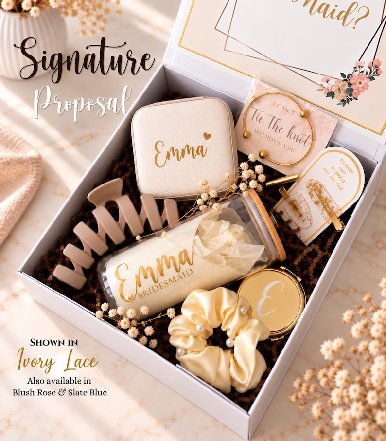 May include: A white gift box containing a beige jewelry case with the name Emma, a glass tumbler with a bamboo lid labeled Emma Bridesmaid, a matte beige hair claw, a cream satin scrunchie with pearls, a gold compact mirror, and a gold bangle.