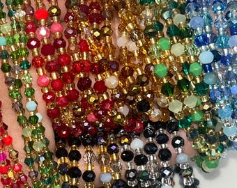 May include: A collection of beaded bracelets in various colors, including red, green, gold, black, and blue. The bracelets feature faceted beads and gold-colored spacers, creating a sparkling and colorful display. These bracelets are a fashion accessory.