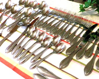 May include: A collection of polished silverware, including spoons, forks, and knives, arranged on a striped tablecloth. The silverware has a reflective surface, and the arrangement suggests a formal dining setting.
