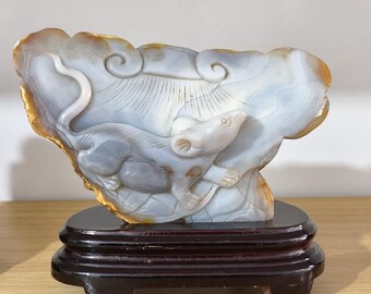 May include: A carved stone sculpture of two rats, one light gray and one off-white, nestled within a cloud-like formation. The sculpture is mounted on a dark brown wooden base. The stone has a marbled appearance with shades of gray, white, and gold.