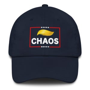 以下が含まれることがあります： ネイビーブルーの野球帽。前面には、白い「CHAOS」の文字、金色の髪のグラフィック、白い星が描かれた赤い長方形があります。