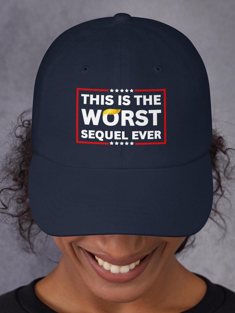 Pu&ograve; includere: Cappellino da baseball blu navy con la scritta "THIS IS THE WORST SEQUEL EVER" in lettere bianche all'interno di un rettangolo rosso. Il cappellino presenta un piccolo disegno di capelli gialli. Il cappello &egrave; indossato da una persona.