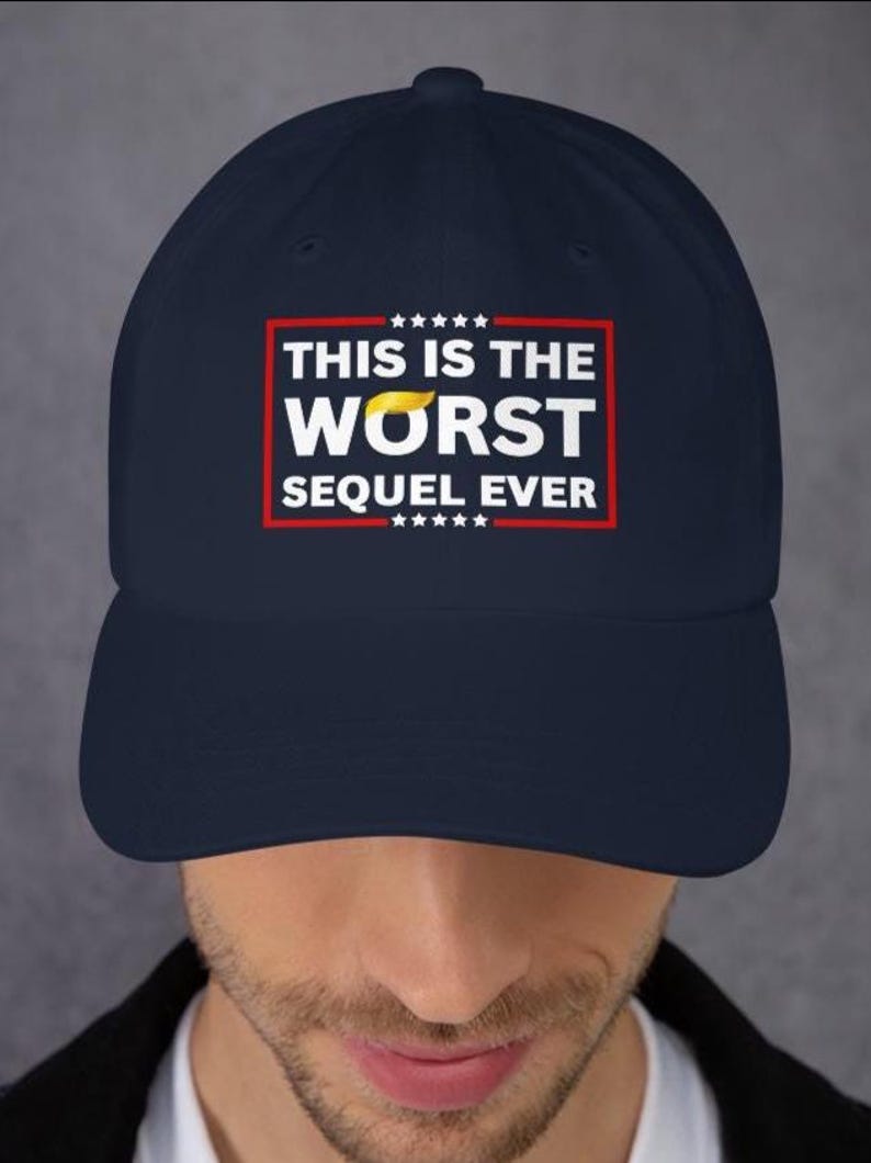 Pu&ograve; includere: Cappellino da baseball blu navy con la scritta "THIS IS THE WORST SEQUEL EVER" in lettere bianche all'interno di un rettangolo rosso. La parola "WORST" ha un disegno giallo a forma di capelli sopra. Il cappellino ha una visiera curva.