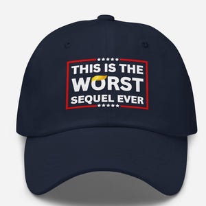 Pu&ograve; includere: Cappellino da baseball blu navy con la scritta "THIS IS THE WORST SEQUEL EVER" in lettere bianche all'interno di un rettangolo rosso. La parola "WORST" ha una grafica di capelli gialli sopra. Il cappellino ha una visiera curva e una corona rotonda.