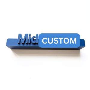 May include: A blue 3D-printed sign with the word "Mid" in bold letters and a blue rectangular tag that reads "CUSTOM" in white letters. The sign is set against a white background.