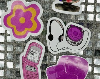 May include: A set of nine stickers featuring various designs, including a disco ball, a flower, a cell phone, headphones, a CD player, a chair, and a small suitcase. The stickers are all pink, purple, and yellow.