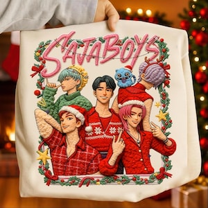Puede incluir: Bolso tote color crema con un diseño bordado de personajes de estilo anime con atuendos navideños. El texto "SATA BOYS" está arqueado en la parte superior en rosa. El diseño incluye una corona, estrellas y lazos.