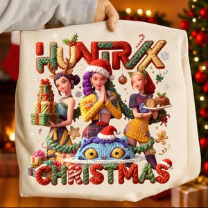Puede incluir: Un bolso tote navideño crema con las palabras "HUNRX" y "CHRISTMAS" en rojo y verde. El diseño incluye tres figuras femeninas estilizadas, regalos y un gato azul con un gorro de Papá Noel.