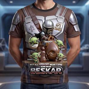 Puede incluir: Camiseta marr&oacute;n con un dise&ntilde;o de un personaje al estilo Mandaloriano y figuras de Grogu, con el texto "#1 DAD". El dise&ntilde;o incluye los nombres "Emily", "Daniel", "Anna" y "Alex". Tambi&eacute;n est&aacute; presente el texto "NOT ALL HEROES WEAR CAPES SOME WEAR BESKAR".