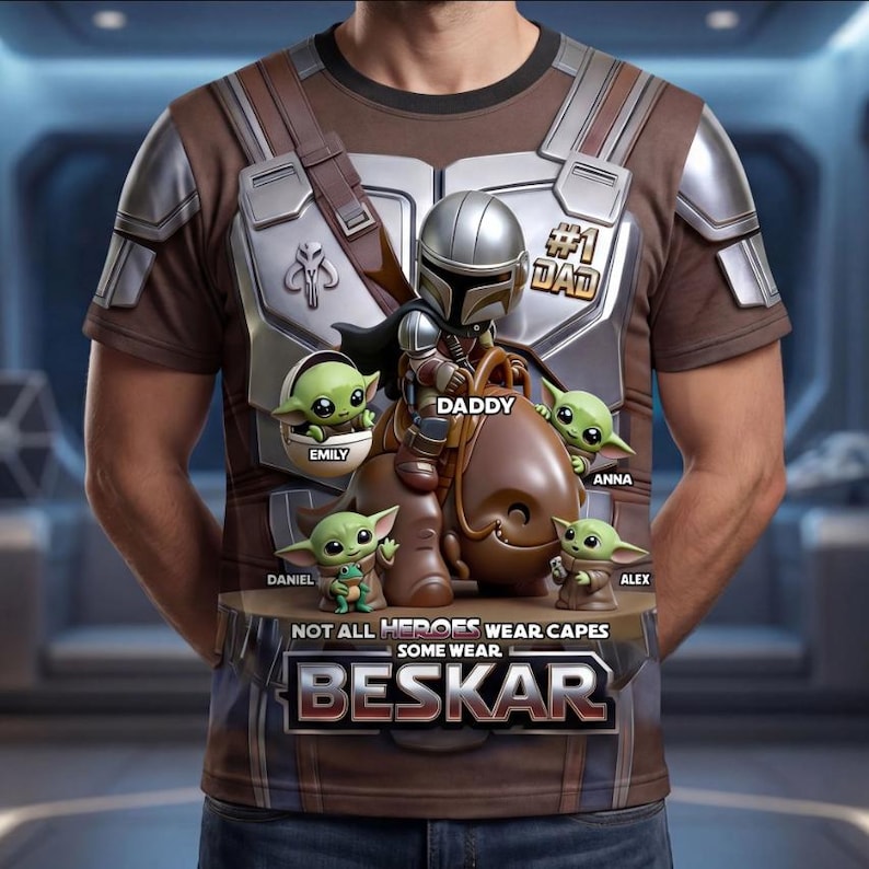 Puede incluir: Camiseta marr&oacute;n con un dise&ntilde;o de un personaje al estilo Mandaloriano y figuras de Grogu, con el texto "#1 DAD". El dise&ntilde;o incluye los nombres "Emily", "Daniel", "Anna" y "Alex". Tambi&eacute;n est&aacute; presente el texto "NOT ALL HEROES WEAR CAPES SOME WEAR BESKAR".