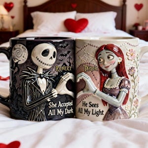 May include: Two ceramic mugs featuring characters from The Nightmare Before Christmas. One mug depicts Jack Skellington, the other Sally. The mugs are black and cream-colored, with the names "Robert" and "Taylor" and the phrases "She Accepted All My Dark" and "He Sees All My Light."
