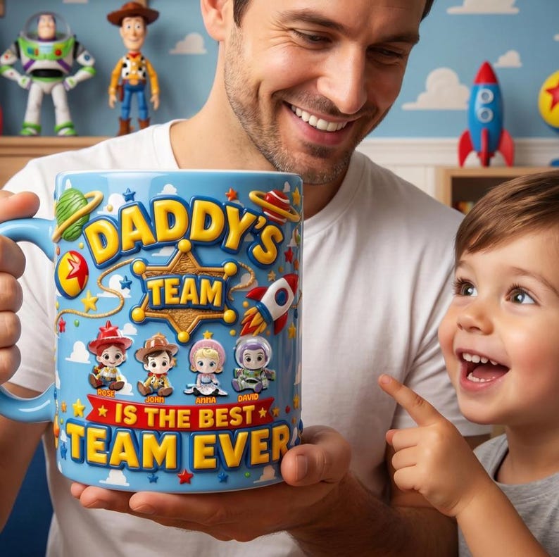 May include: A blue ceramic mug with the text "DADDY'S TEAM IS THE BEST TEAM EVER" and cartoon character illustrations. The mug has a blue handle and is held by a person. Toy Story figures are visible in the background.