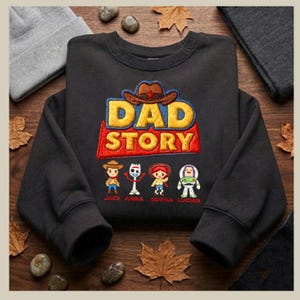 May include: Black sweatshirt featuring the embroidered text "DAD STORY" in yellow, red, and blue, with a cowboy hat graphic. Below the text are four cartoon characters with names: Jack, Anna, Sophia, and Lucian.