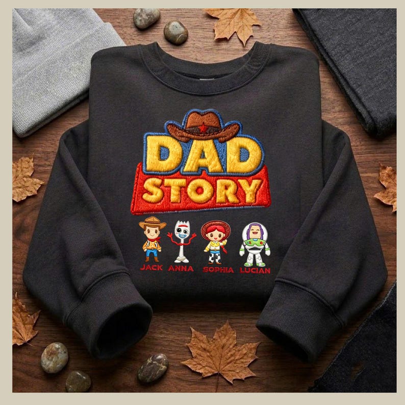 May include: Black sweatshirt featuring the embroidered text "DAD STORY" in yellow, red, and blue, with a cowboy hat graphic. Below the text are four cartoon characters with names: Jack, Anna, Sophia, and Lucian.