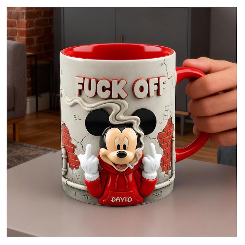 May include: A ceramic mug with a red interior and handle, featuring a 3D Mickey Mouse design. The mug has the words "FUCK OFF" in bold letters and the name "DAVID" on the red hoodie. The character is smoking a cigarette and giving the middle finger.