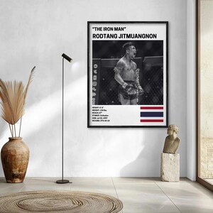 a framed poster of a fighter, with a fighter depicted in a fighting stance. The poster is hanging on a wall, and there is a statue of a person in the foreground.
