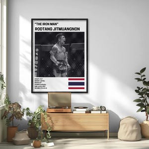 a framed poster of a fighter, hanging on a wall in a room with a wooden table and potted plants.