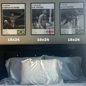 three framed posters of professional boxers, each with a different fighter's name and image, displayed above a bed with white pillows.